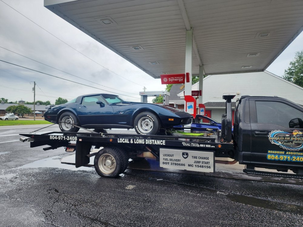 Classic car loaded on a Roadrunner flatbed at a fuel station