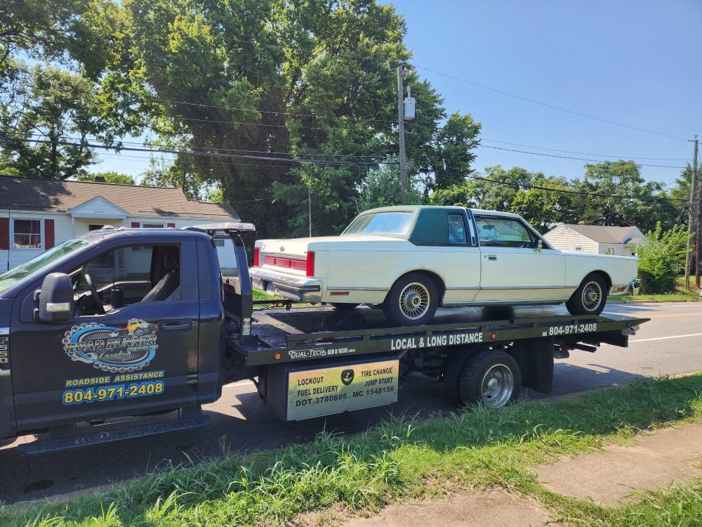 Full-size sedan on a Roadrunner flatbed tow truck